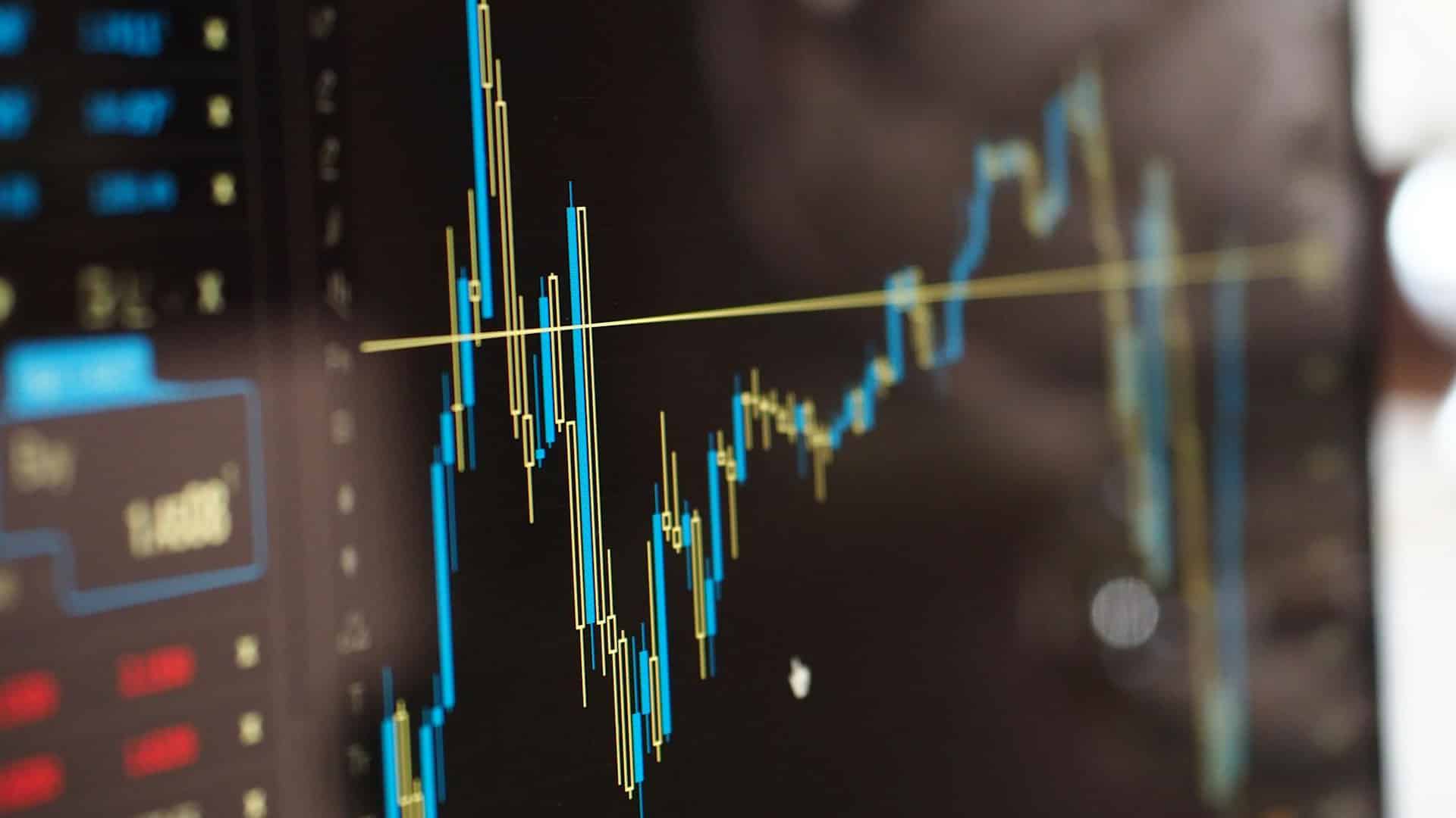 Close-up of a monitor showing blue and yellow financial graphs. Tax