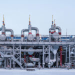 Planta productora de gas cerca de la ciudad de Novi Urengói en el extremo norte de Rusia, uno de los puntos del gasoducto Poder de Siberia 2. La planta está en un entorno nevado, con tres estructuras verticales con válvulas conectadas por tuberías, y una escalera metálica a la izquierda que lleva a una plataforma elevada.