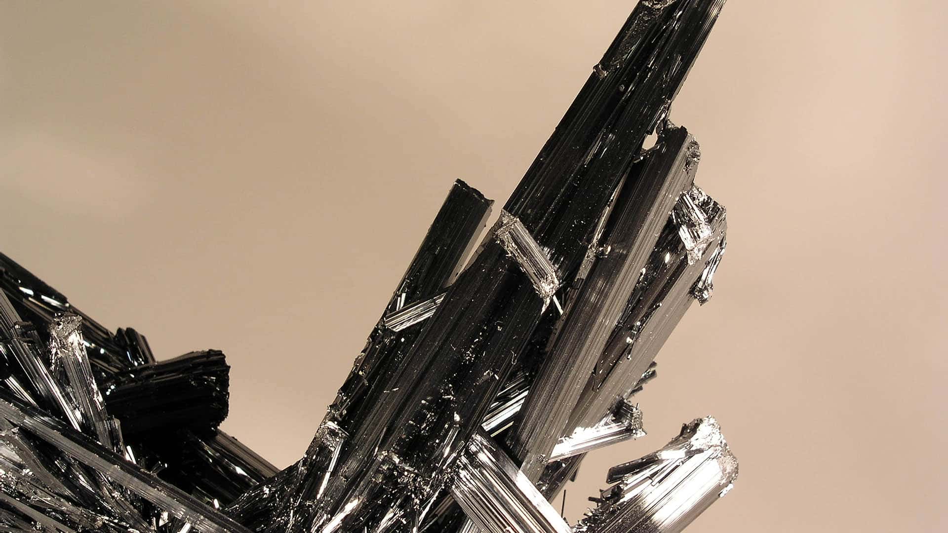 Detail of a piece of antimony ore (the main source of antimony) with a lead-grey metallic colour and iridescent reflections on a sepia background.