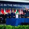 Donald Trump pronuncia su discurso desde el atril tras la firma del acuerdo de alto el fuego entre Israel y Hamás para el fin a la guerra en Gaza durante la cumbre en Sharm el Sheij, Egipto (13/10/2025). Detrás, los líderes mundiales que han acudido al encuentro, de pie, y al fondo banderas de los países representados con una pantalla con las palabras “Peace in the Middle East”.