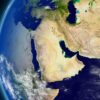 Vista satelital del globo terráqueo centrada en Oriente Medio, con regiones vecinas visibles parcialmente y algunas nubes dispersas sobre la superficie. A la izquierda, la vista se enmarca por el entorno espacial.