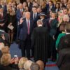 Donald Trump, con la mano levantada, presta juramento al cargo en su segundo mandato como presidente de EEUU ante el presidente del Tribunal Supremo, John Roberts, en la Rotonda del Capitolio (20/01/2025). Lo rodean personalidades políticas y empresariales destacadas, que fotografían la escena con cámaras y teléfonos móviles.