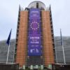 En el frente de la fachada color teja del Edificio Berlaymont, sede de la UE en Bruselas, un gran cartel con el texto “United for our future” y “2024-2029”, con el logo de la sede de la UE. A ambos lados, banderas de la UE y, más atrás, la forma asimétrica de dos de las alas del edificio, de aspecto moderno, con cristal y metal. La imagen fue tomada en la durante el despliegue de la pancarta, en diciembre de 2024.